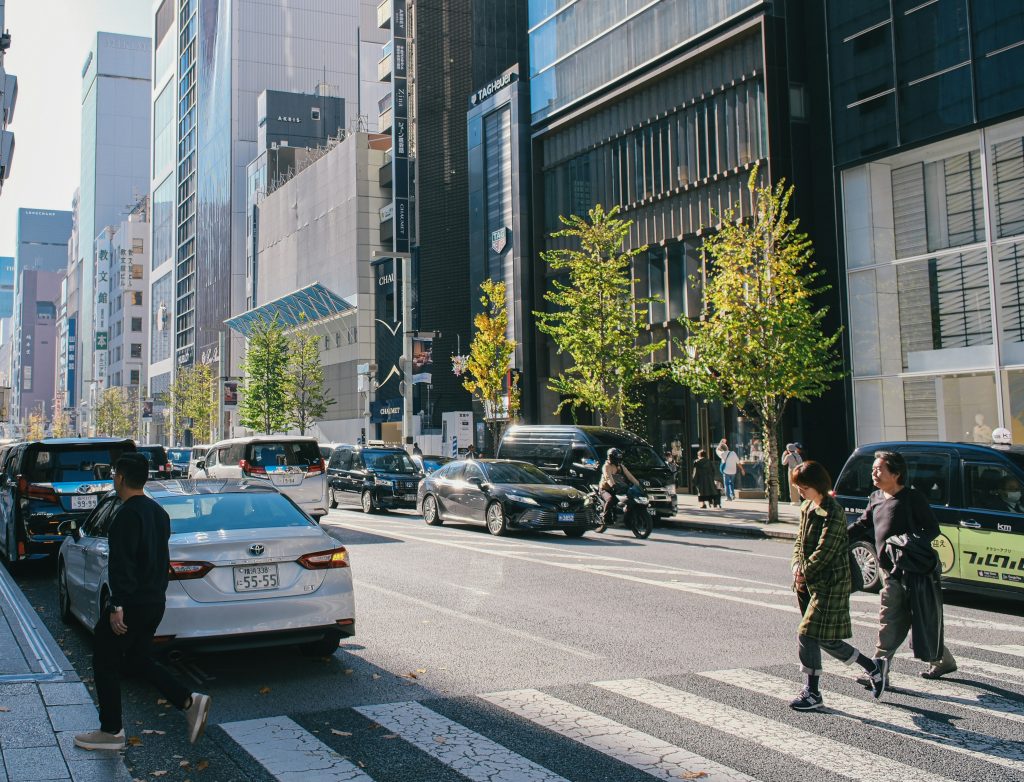 People crossing street in a city with cars