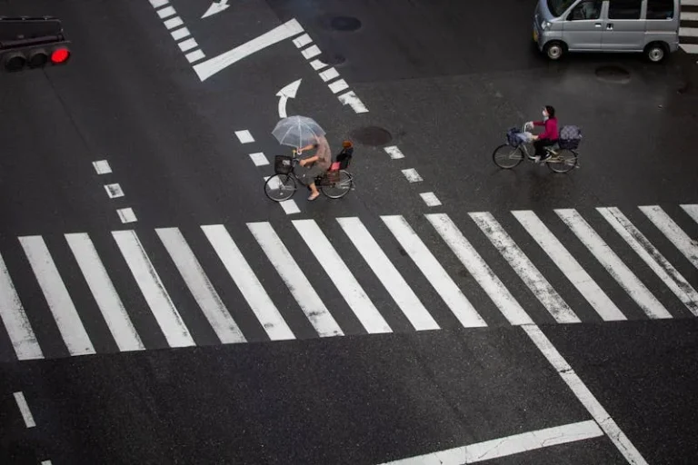 Pedestrians and cyclists crossing a busy city street in rainy weather