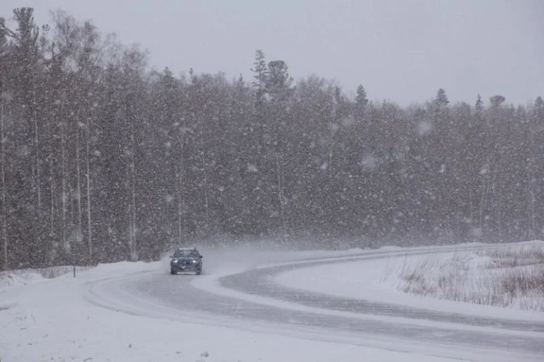 Car navigating a snowy road during winter storm representing black ice accident claims